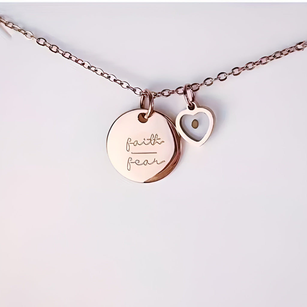 Rose gold necklace with 'faith' and 'heart' charms on a light gray background