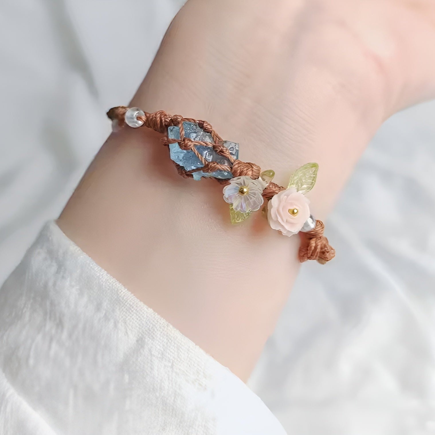 Decorative bracelet with floral elements on a wrist against a light background