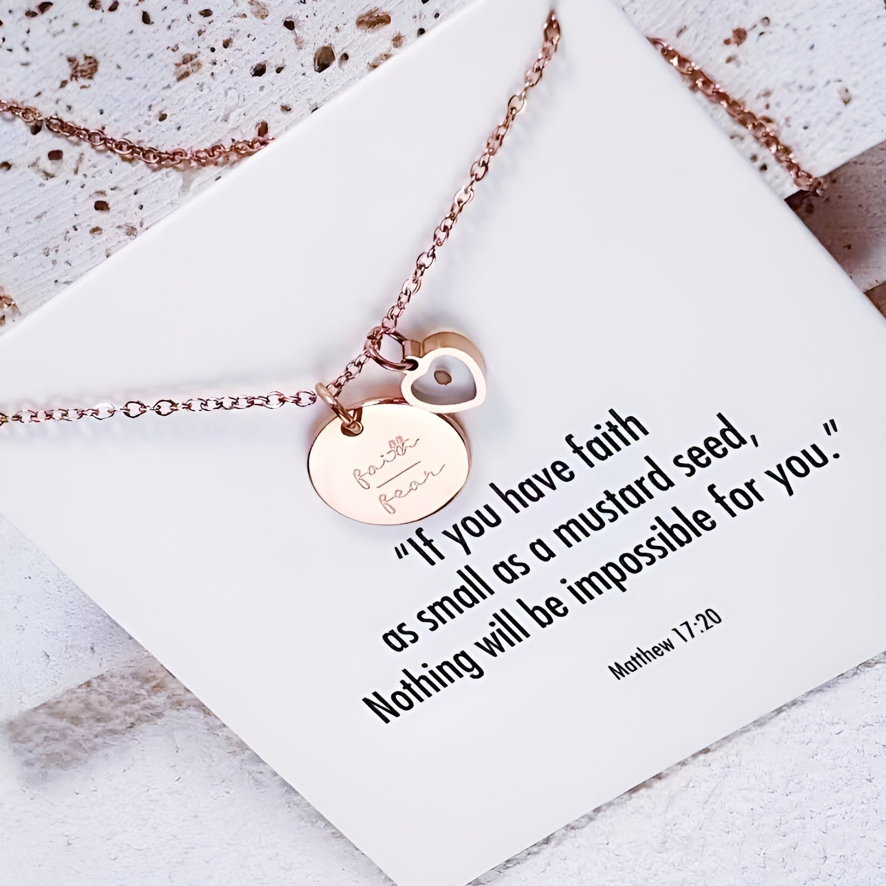 Rose gold necklace with heart pendant and inspirational quote card on a textured surface. Christian Jewellery UK.