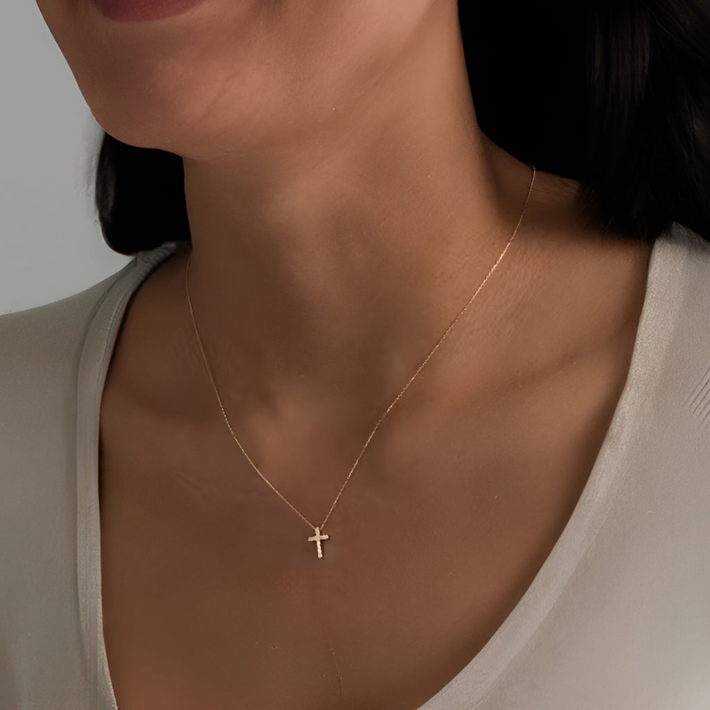 Gold necklace with a small cross pendant on a neutral background. Elegant gold cross pendant for women.