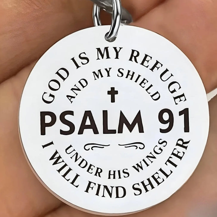 Round metal pendant with engraved text 'GOD IS MY REFUGE AND MY SHIELD PSALM 91 I WILL FIND SHELTER' held in a hand.