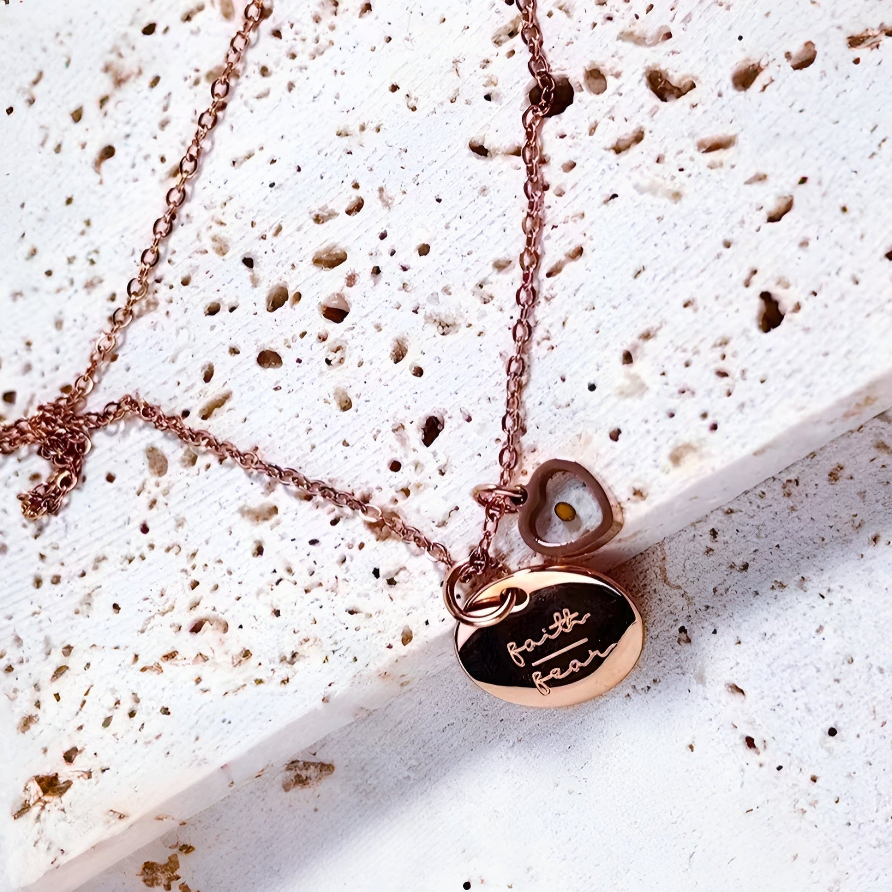 Rose gold necklace with heart and round pendants on a textured white surface. Rose Gold Christian Necklace.