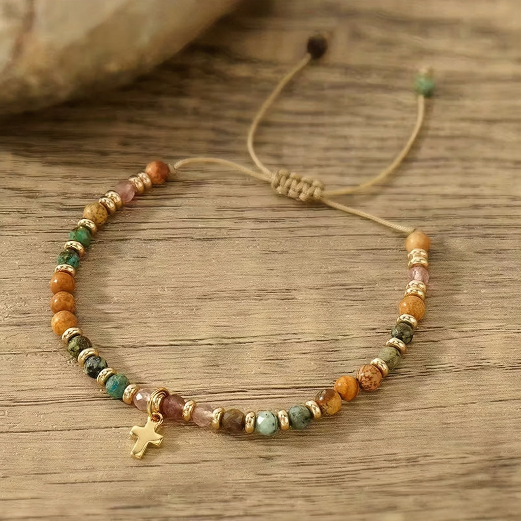 Beaded bracelet with a cross charm on a wooden surface