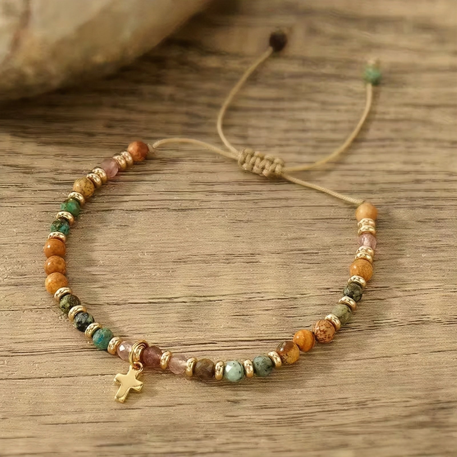 Beaded bracelet with a cross charm on a wooden surface