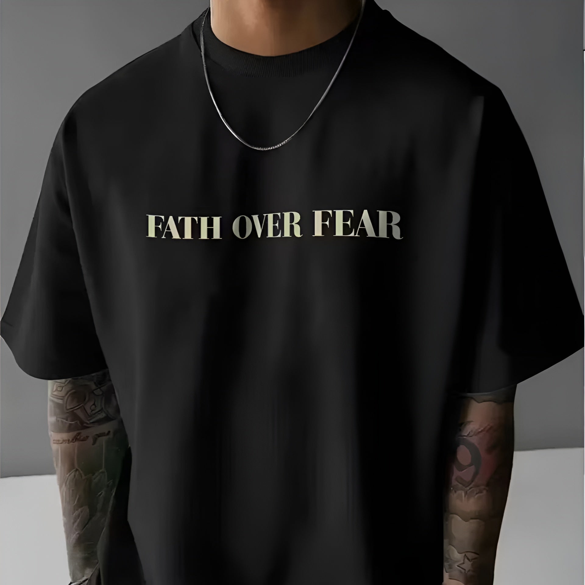 Person wearing a black t-shirt with 'FAITH OVER FEAR' text on a grey background
