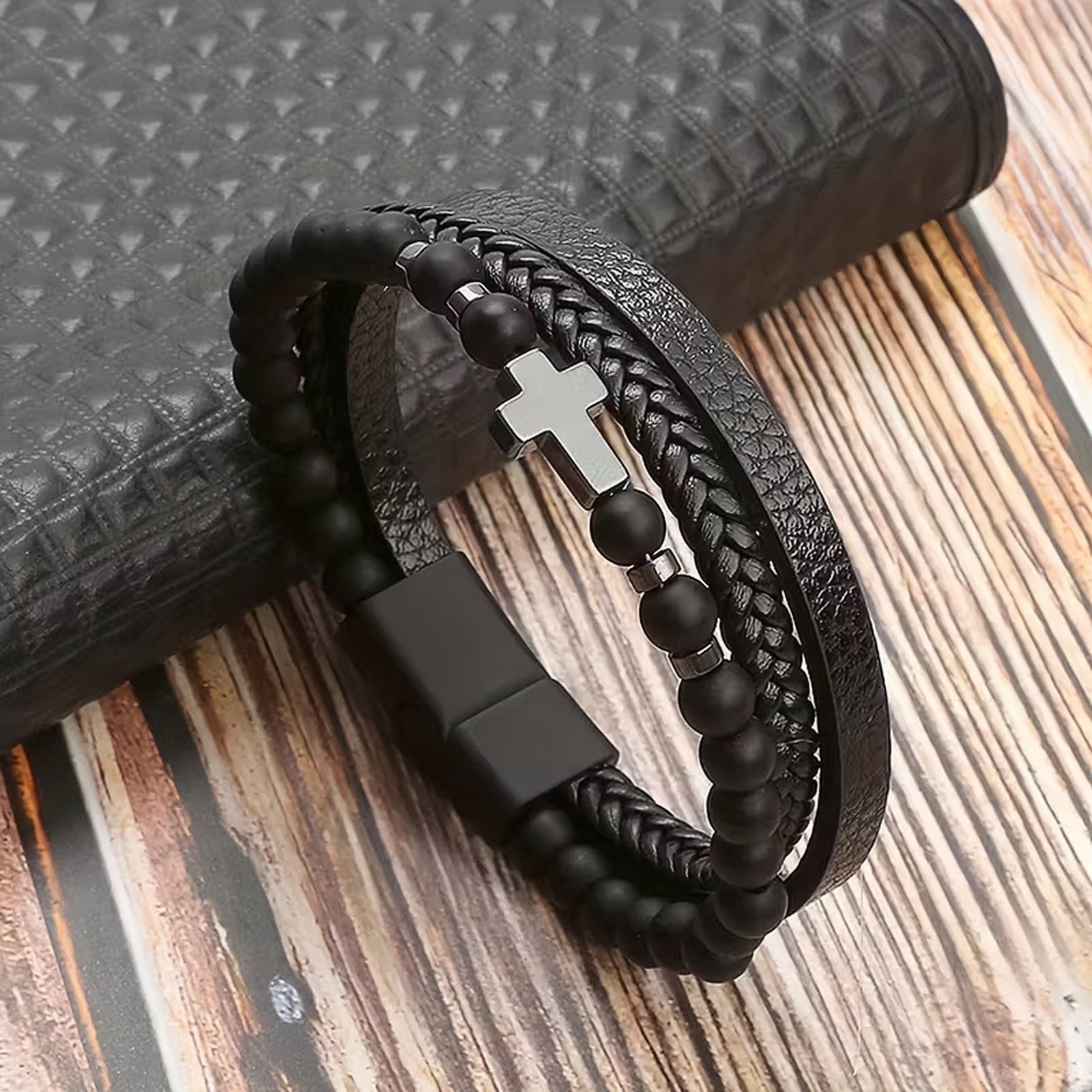Black braided leather bracelet with  Cross, features beads on a wooden surface, faith gifts for him