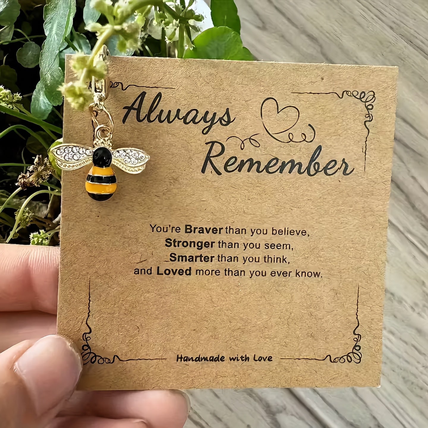 Card with bee charm and inspirational quote on a wooden surface