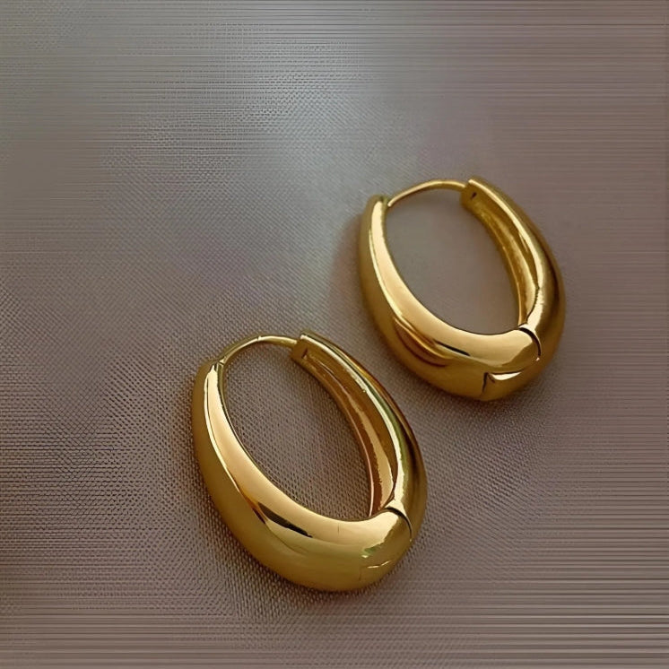 Gold hoop earrings on a metallic surface