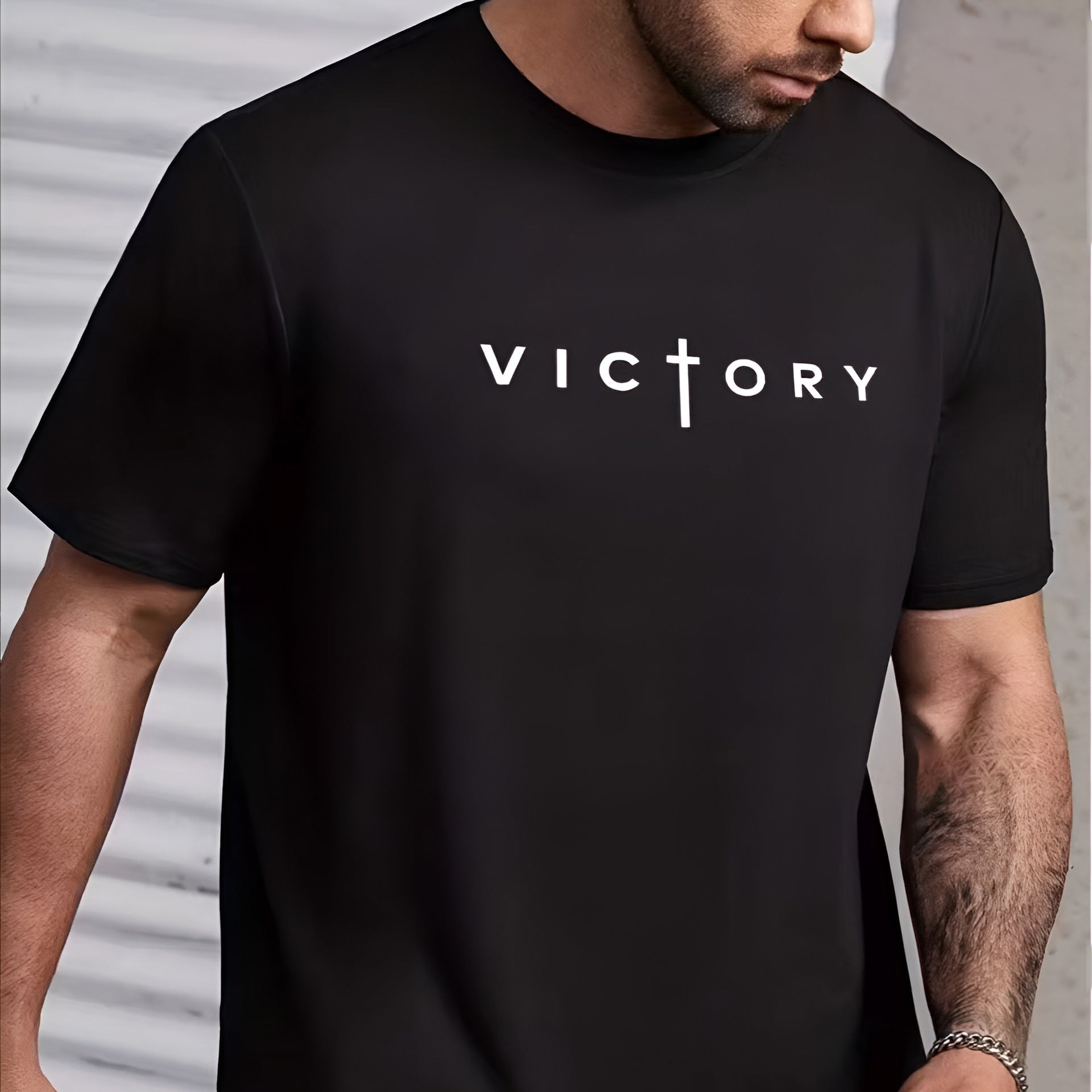 Person wearing a black t-shirt with 'VICTORY' printed on it against a neutral background