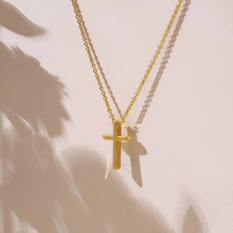 Gold cross necklace on a light background
