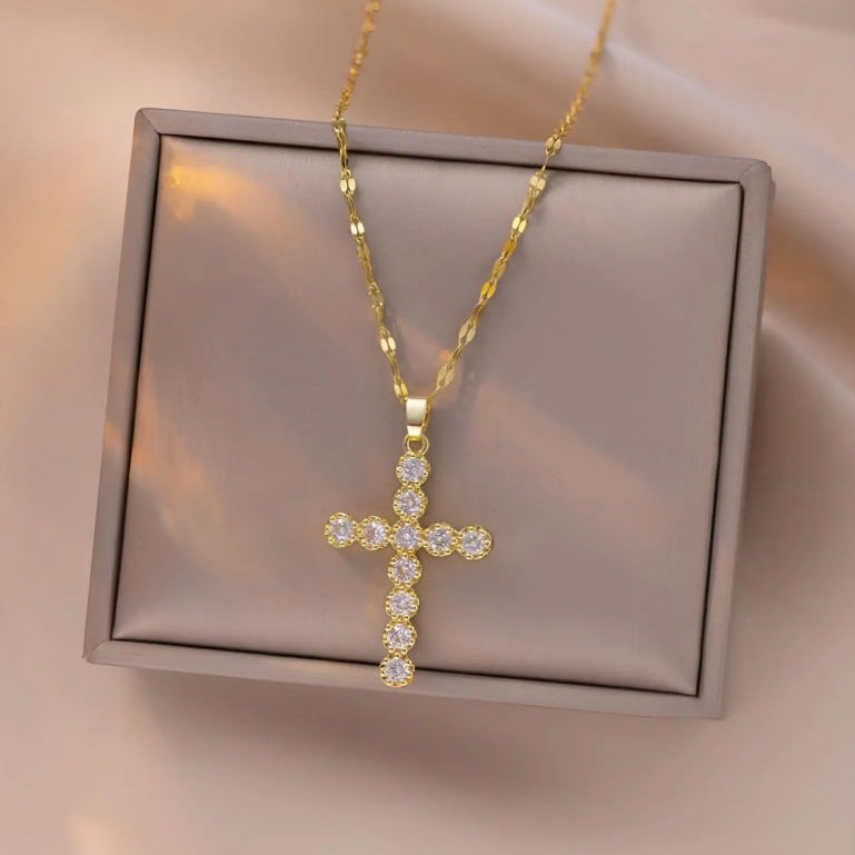 Gold cross necklace on a Grey jewellery box with a soft pink background