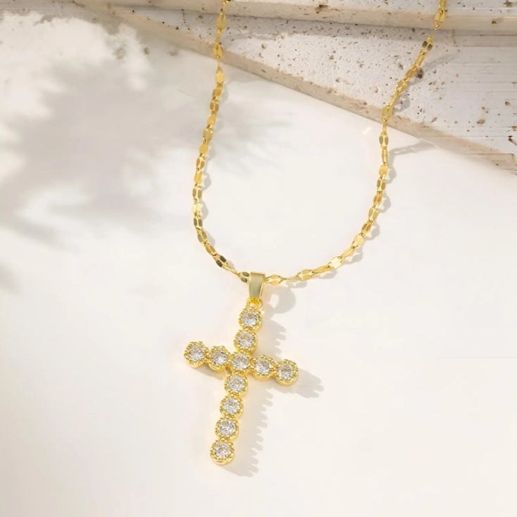 Gold necklace with a cross pendant on a light background